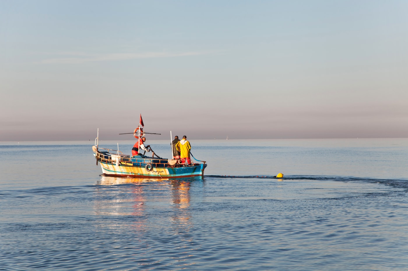 A fishing boat returning to the harbor at sunrise